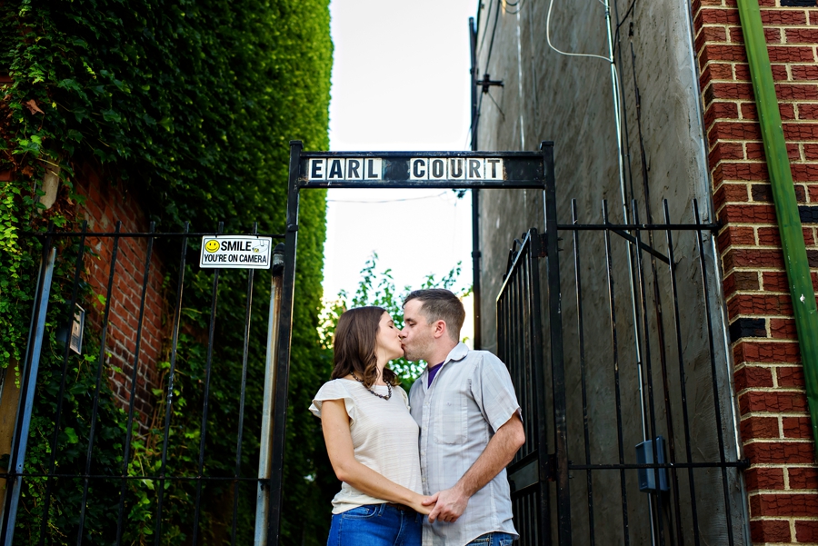 An engaged couple kiss outside of their old house in fishtown.